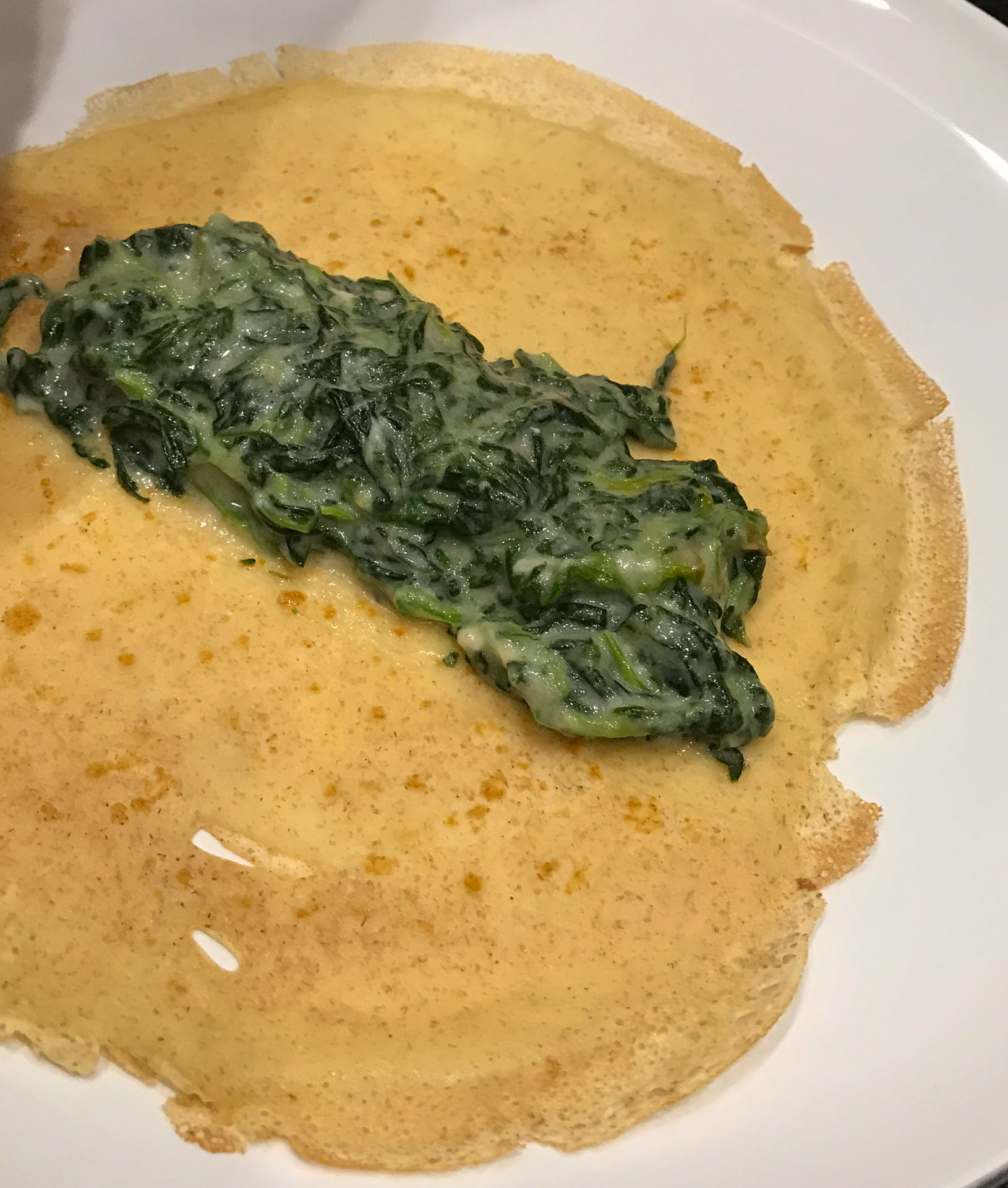spinach crepe filling spooned onto flat crepe